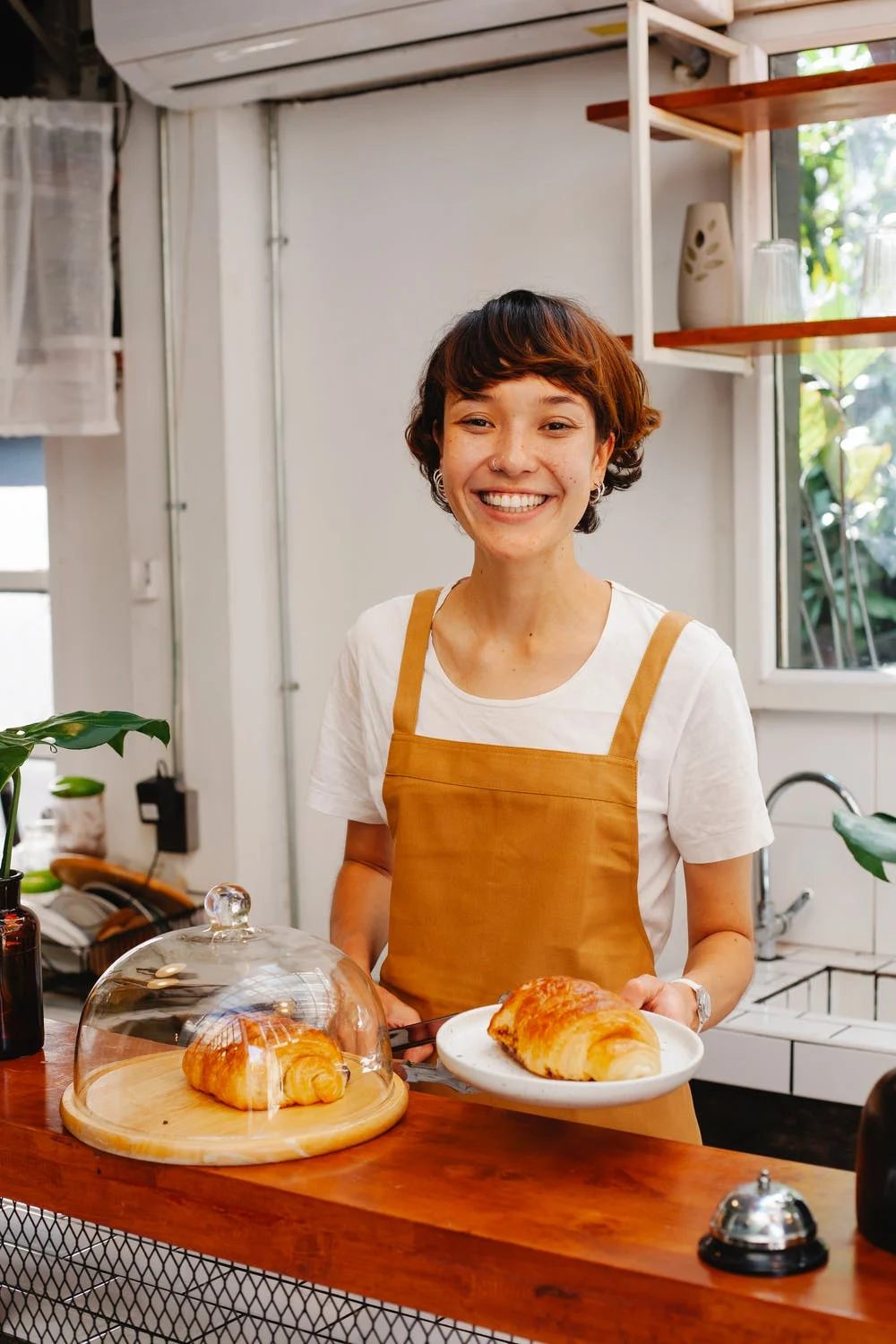 Woman in apron presenting pastries, restaurant business owner.