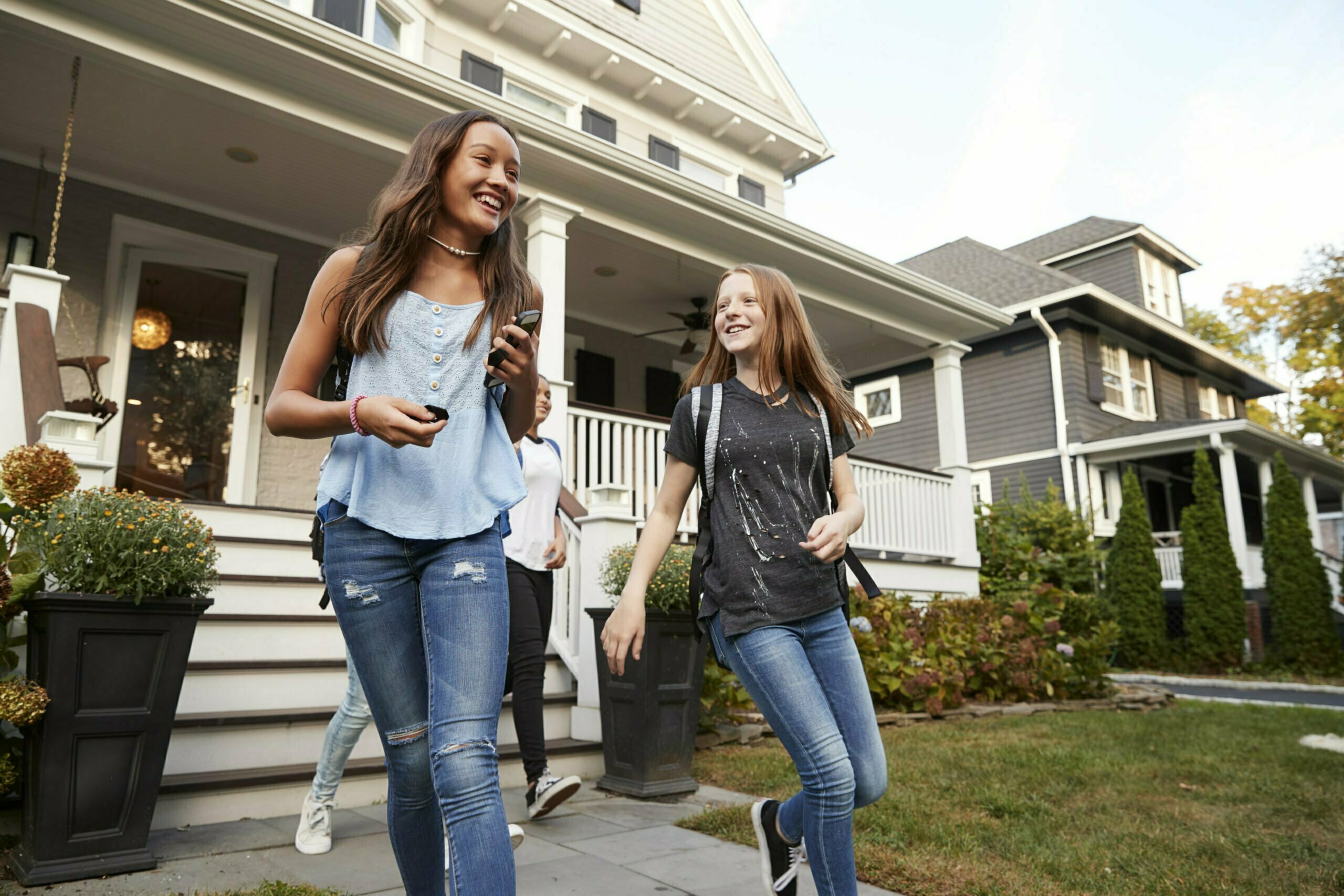 Young teen girlfriends leaving a house for school