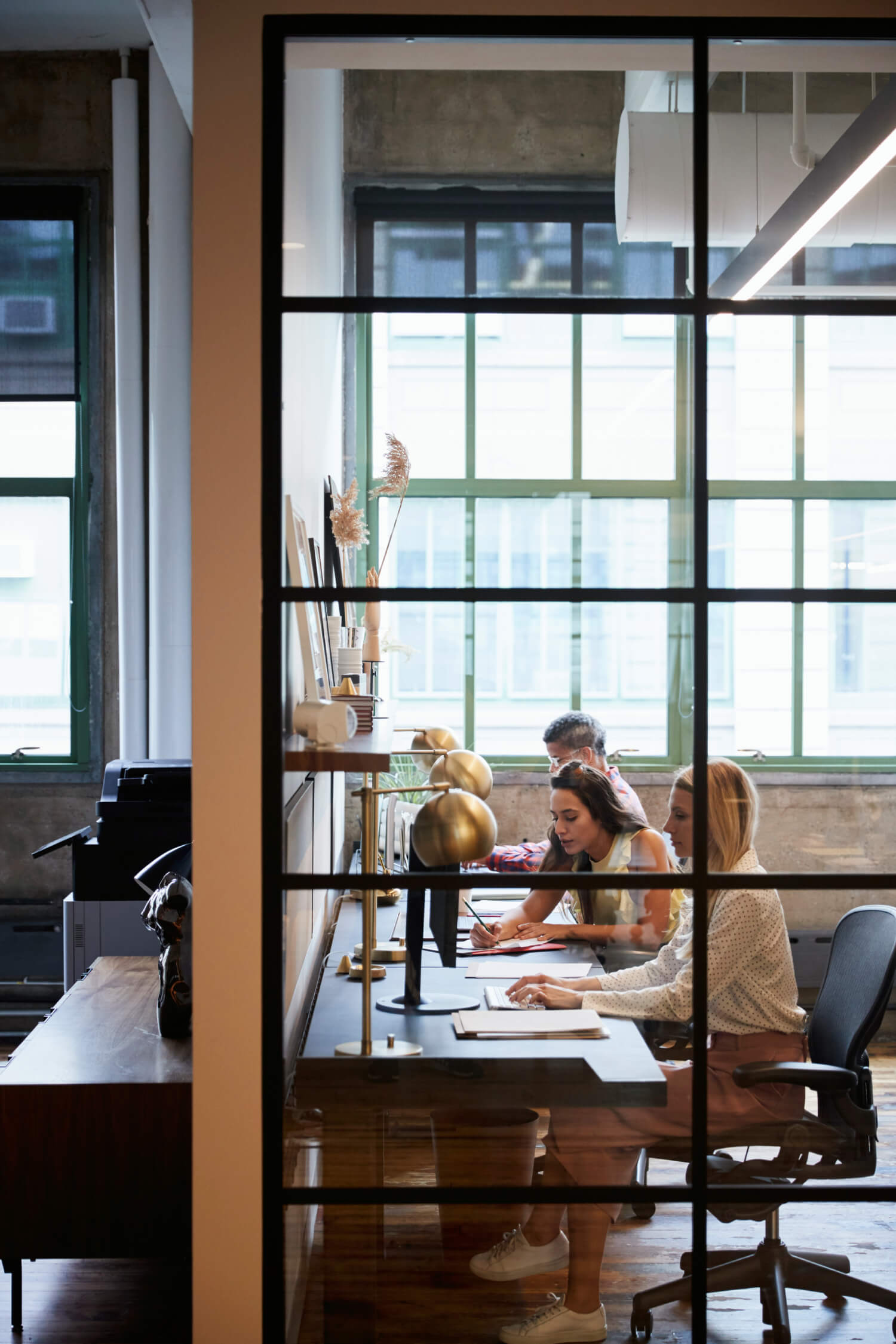 a group of people sitting at a table in a room with windows
