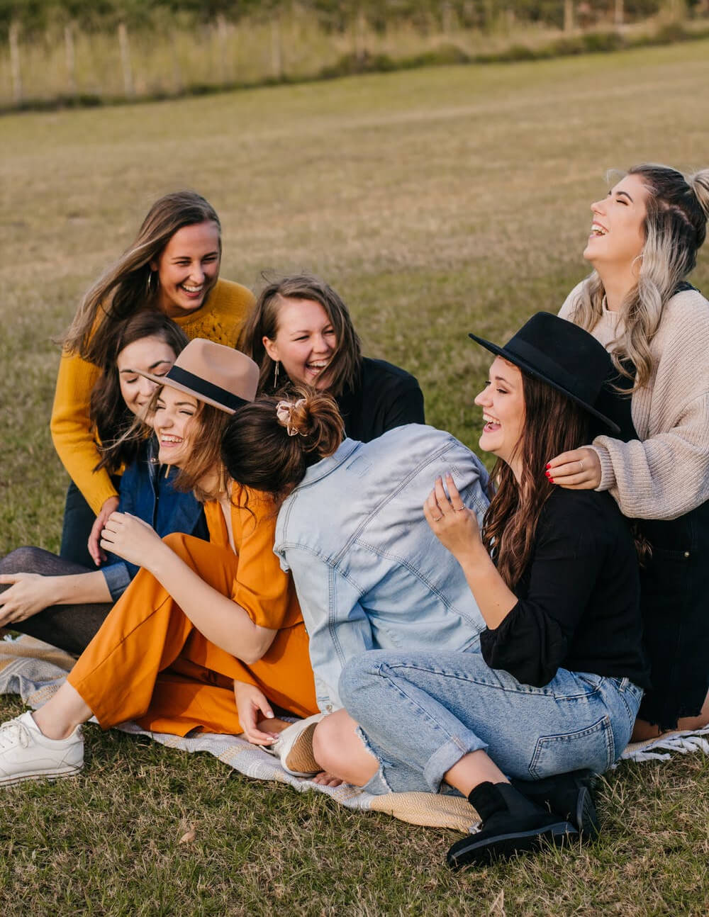 a group of girls in graduation gowns and caps sitting on the ground