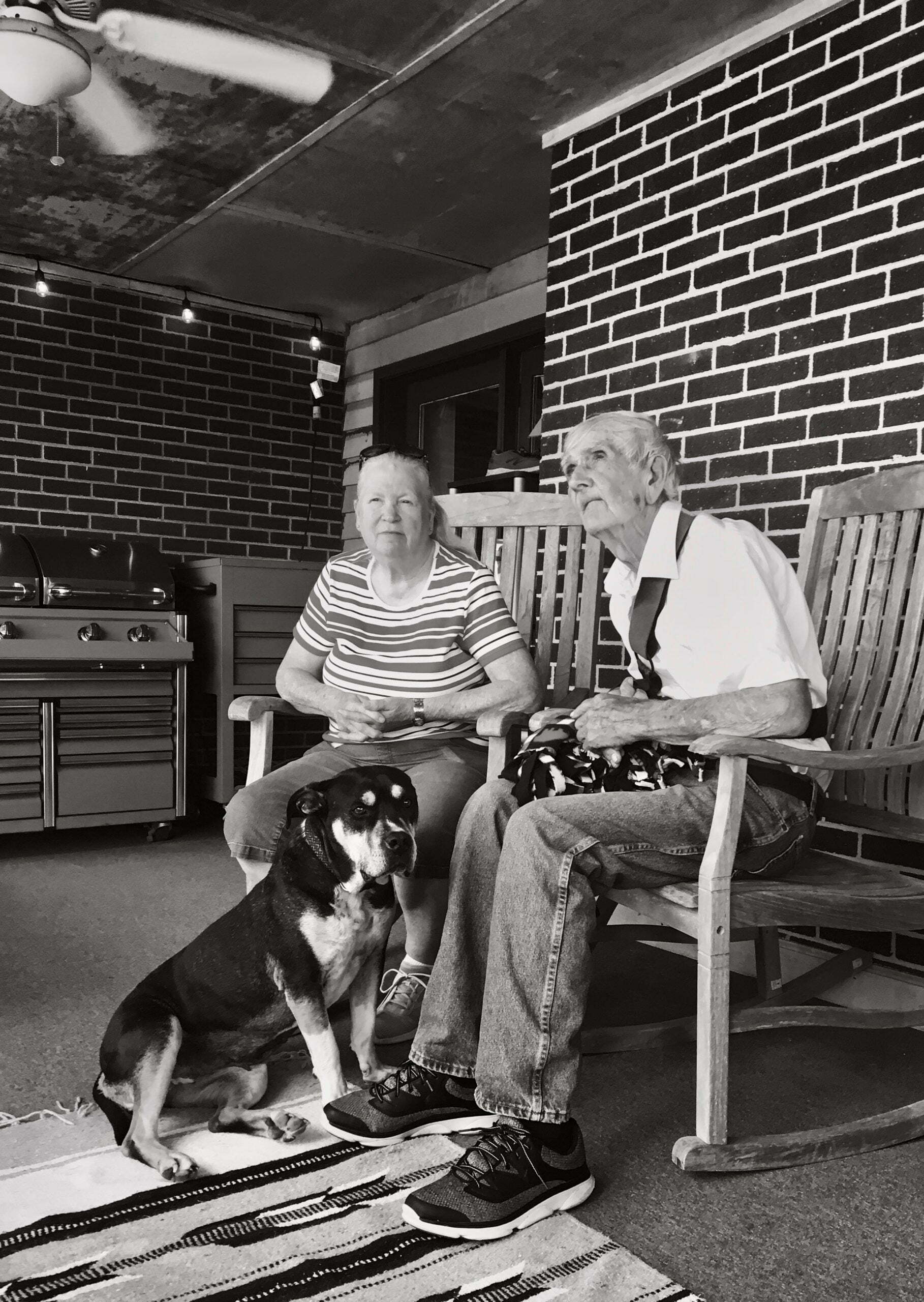 a dog sitting on a chair next to a woman and a man