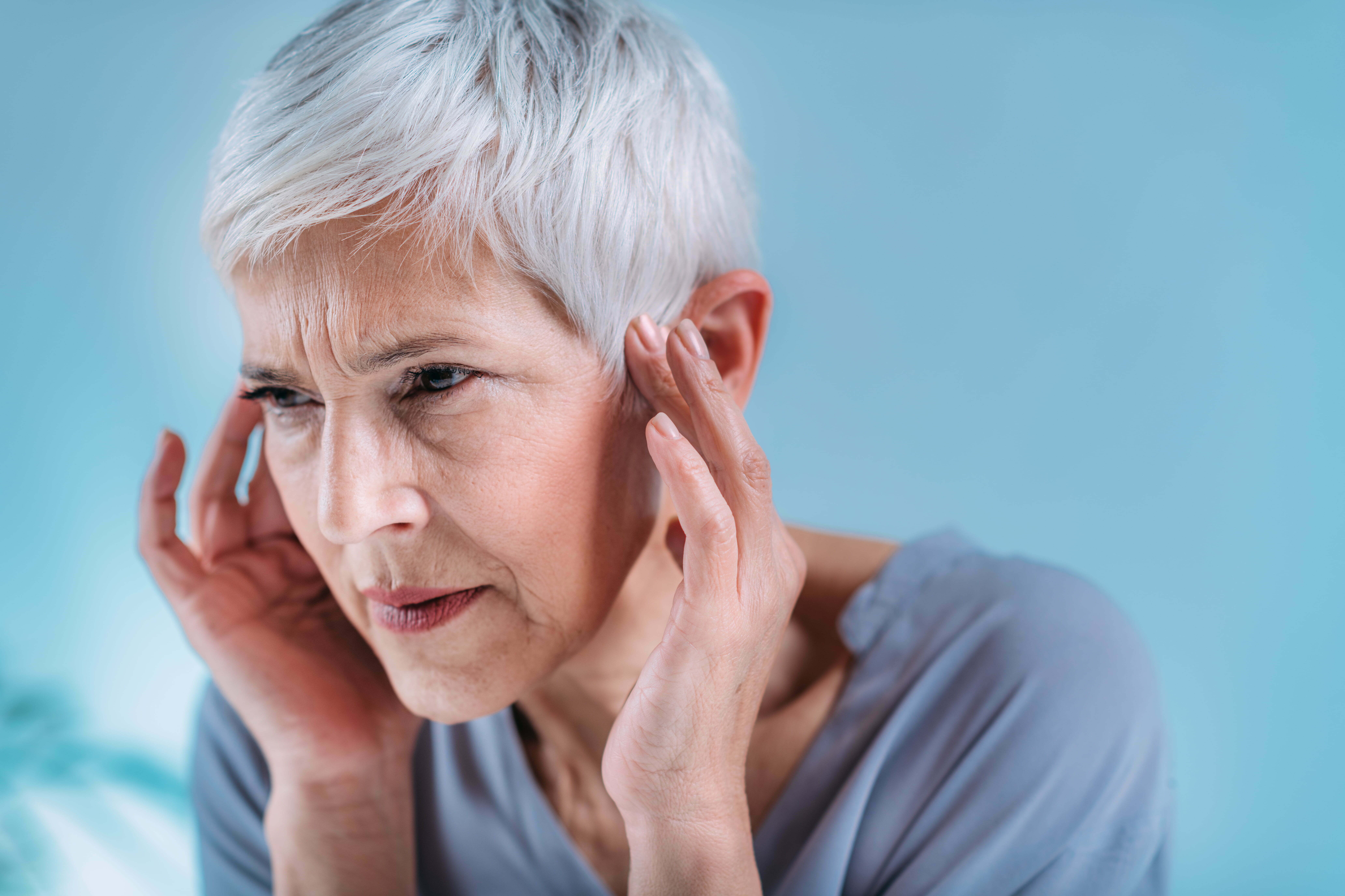 older woman holding her ears