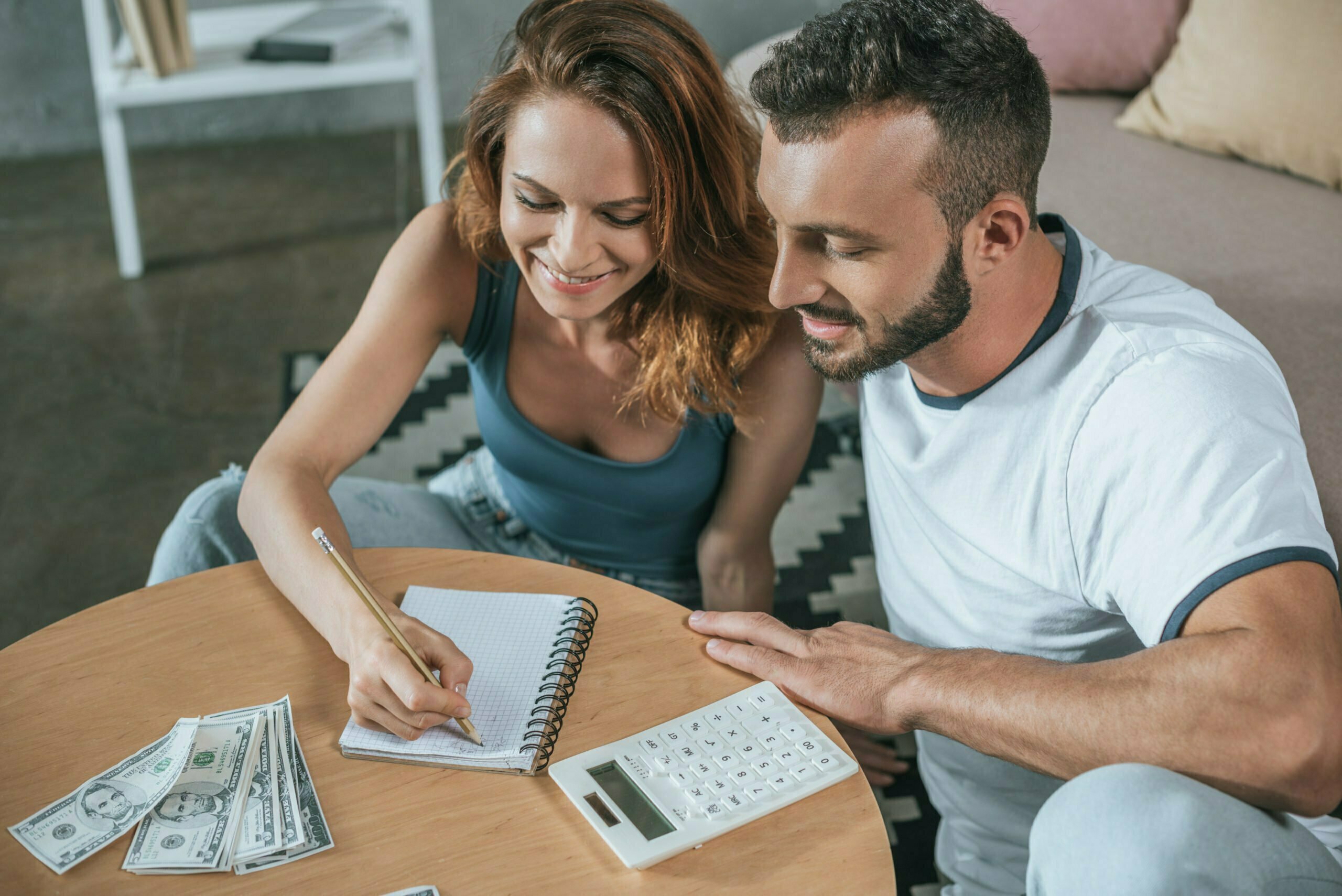 couple planning family budget and writing something to notebook in living room