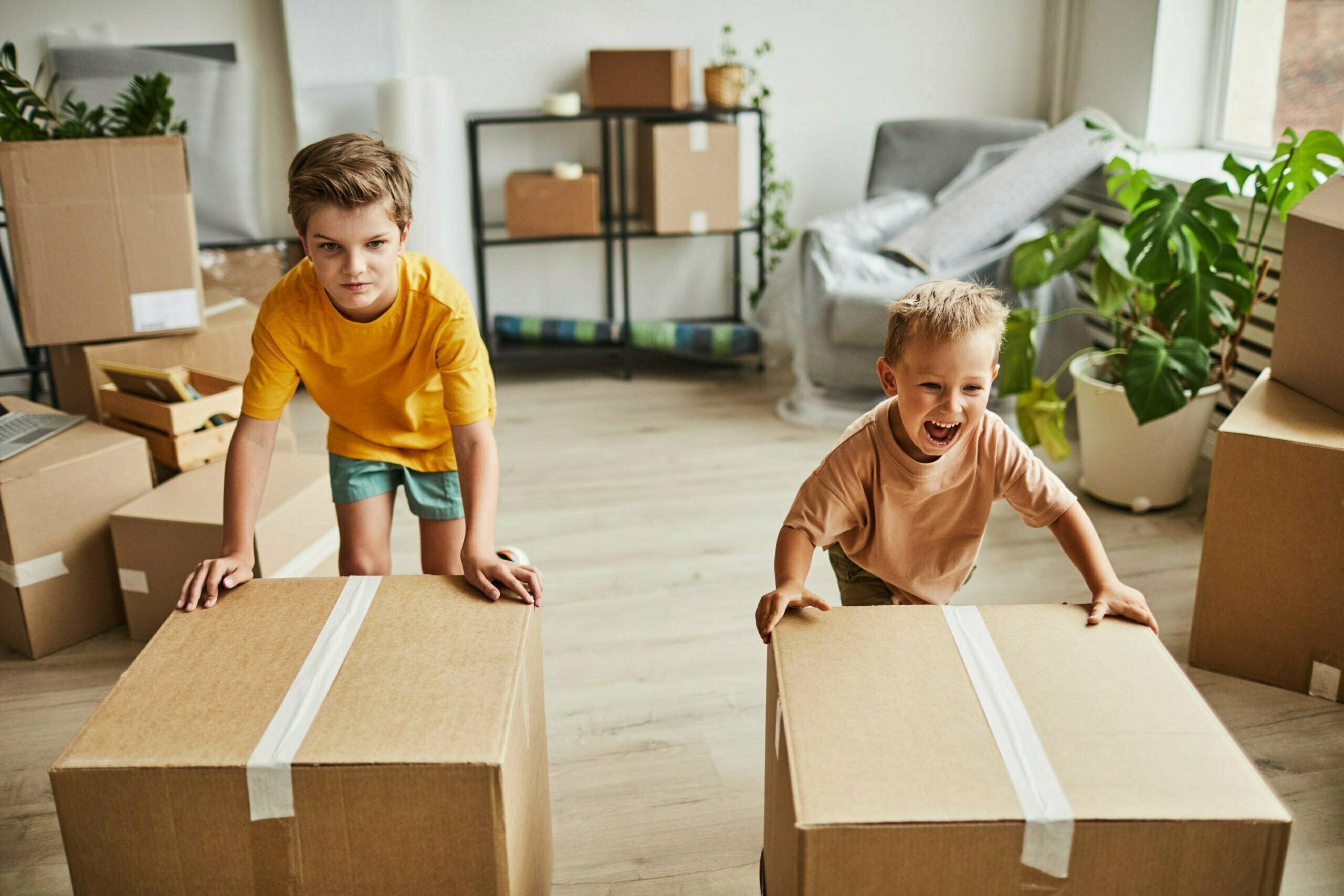 Portrait of two boys moving cardboard boxes while family relocating to new house, copy space