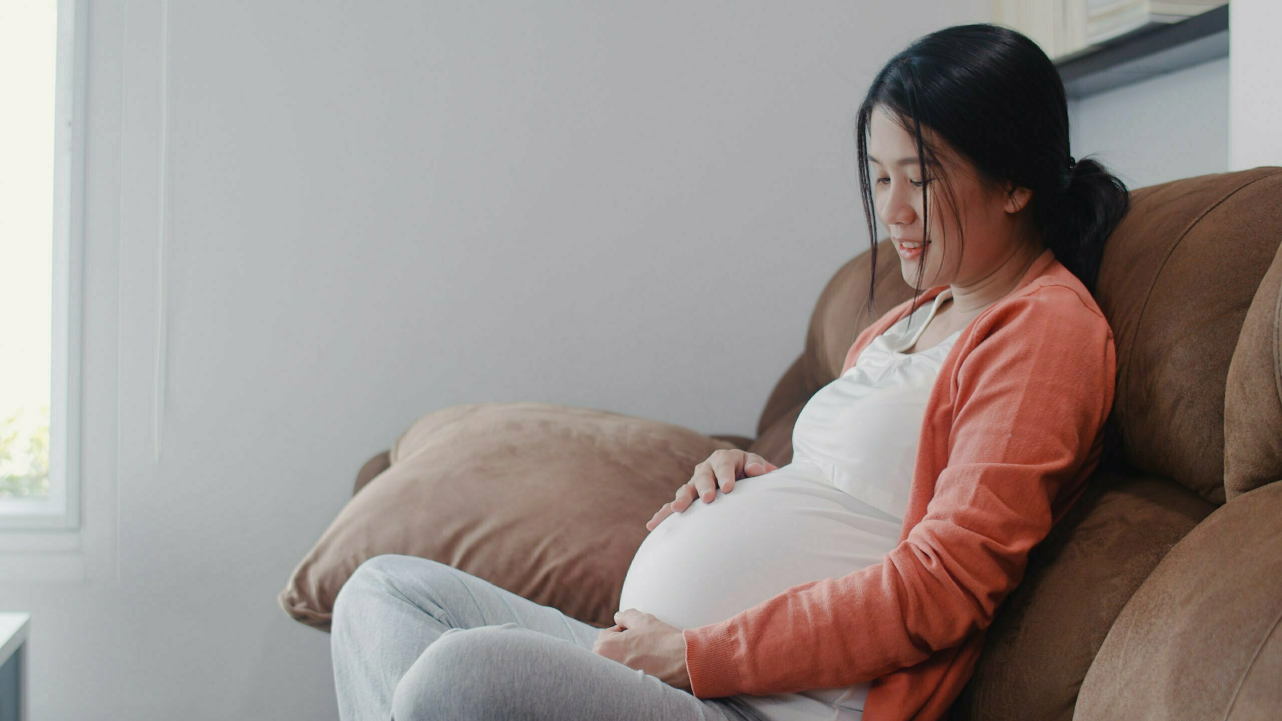 Young Asian Pregnant woman holding her belly talking with her child.