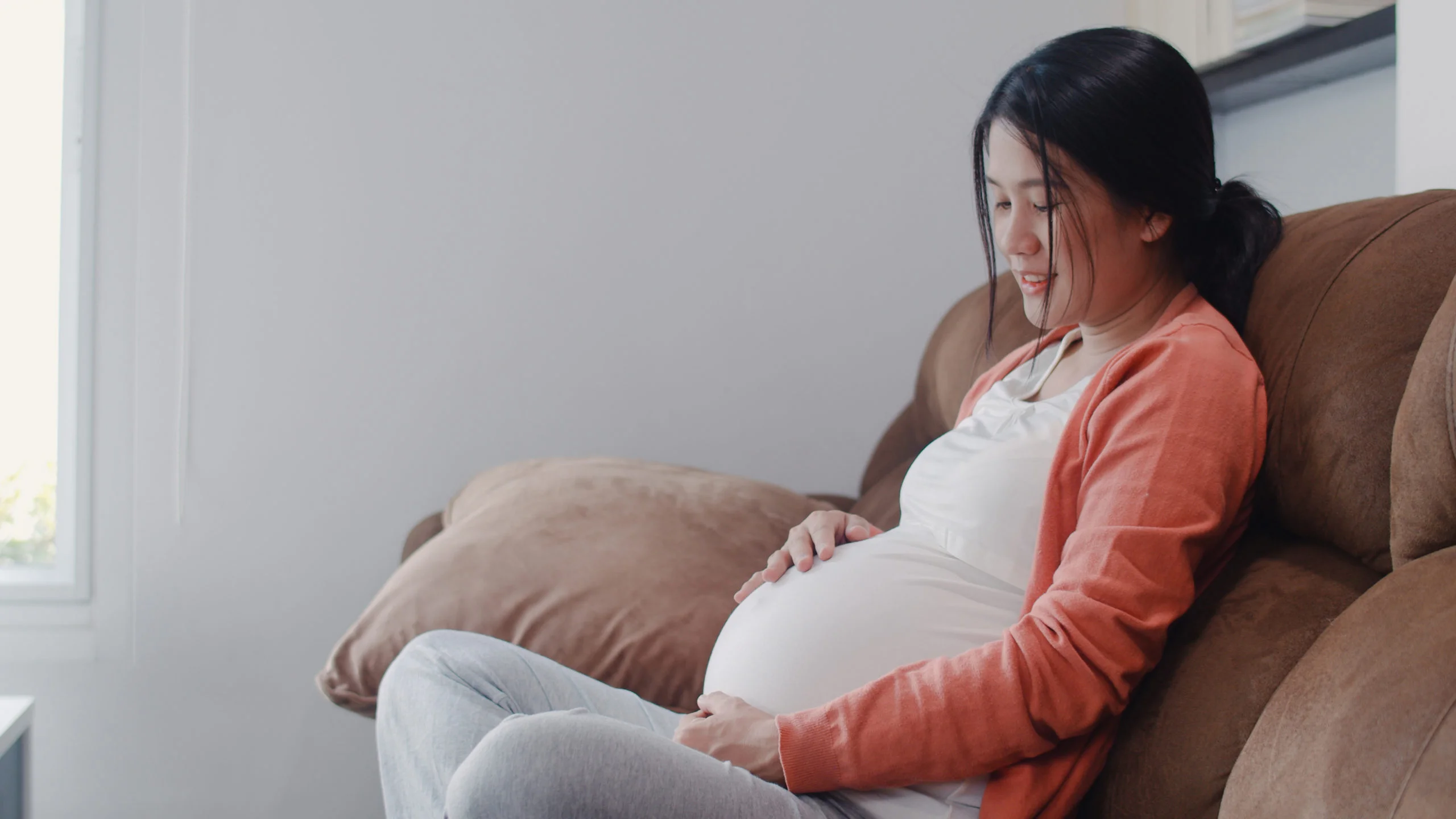 Young Asian Pregnant woman holding her belly talking with her child.